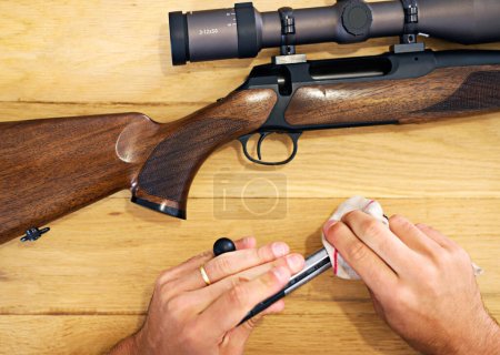 El mantenimiento regular es esencial para todos los propietarios de armas. Vista recortada de un hombre limpiando su rifle