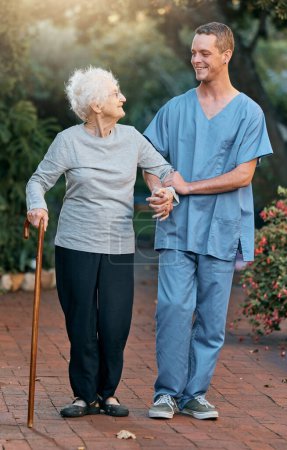 Foto de Enfermera, mujer mayor y caminando en el parque para la salud y el bienestar. Fisioterapia, rehabilitación y anciana jubilada con discapacidad y bastón hablando con el médico al aire libre en el jardín - Imagen libre de derechos