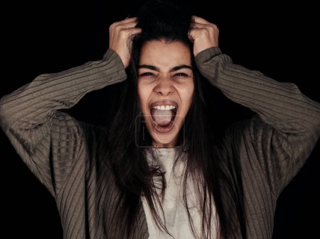 Foto de Estrés, ansiedad y mujer gritando con frustrado, deprimido de sensación de problemas de salud mental. Retrato de una joven española con rabia y cara loca tirando del pelo con esquizofrenia. - Imagen libre de derechos