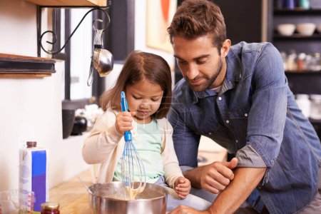 Photo for Learning the basics of breakfast. A cute little girl helping her dad make pancakes at home - Royalty Free Image
