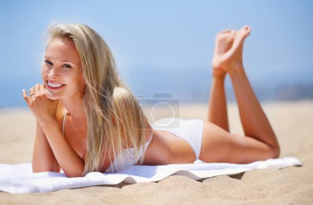 Tomándolo con calma en la playa. Una mujer besada por el sol relajándose en la playa en bikini