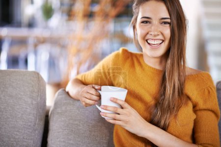 Kaffee und Freizeit. Ausschnittbild einer hübschen jungen Frau, die Kaffee trinkt, während sie auf dem Sofa sitzt