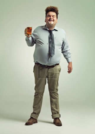 Photo for Beer is good. an overweight man celebrating while holding a pint of beer - Royalty Free Image