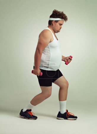 Foto de ¿Puedes verlo funcionar? Vista lateral de un hombre con sobrepeso levantando pesas - Imagen libre de derechos