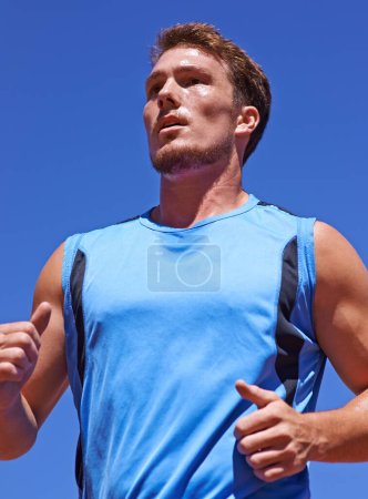 Photo pour Tester son endurance. Prise de vue en angle bas d'un jeune athlète masculin courant dans une course - image libre de droit