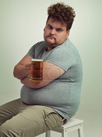 Foto de Beber solo no es divertido. un hombre con sobrepeso de aspecto triste sosteniendo una cerveza - Imagen libre de derechos