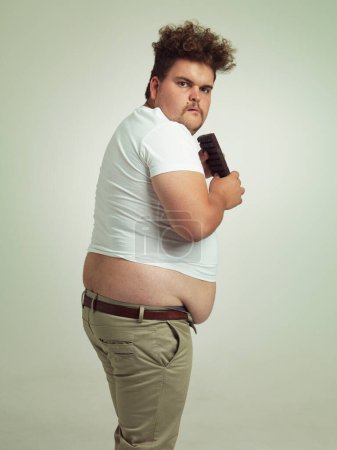 Photo for Its my precious. an overweight man eating a bar of chocolate - Royalty Free Image
