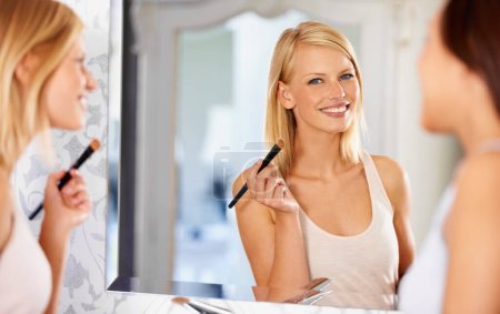 Foto de Realmente te ves impresionante. una joven mujer que se maquilla delante de un espejo mientras su amiga está de pie - Imagen libre de derechos