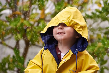 Téléchargez les photos : Rien ne peut me mouiller ici. un jeune garçon jouant dehors sous la pluie - en image libre de droit