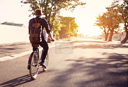 Photo for Taking a ride on the brighter side of life. Rearview shot of a young man riding a bicycle outdoors - Royalty Free Image