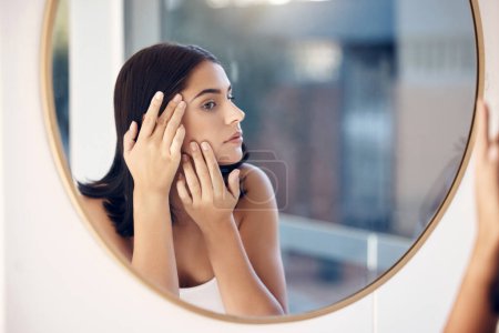 Skincare, facial and woman by a mirror to check for acne breakout or pimples while cleaning face in bathroom. Beauty, wellness and healthy girl grooming or checking cosmetics results or prp progress.