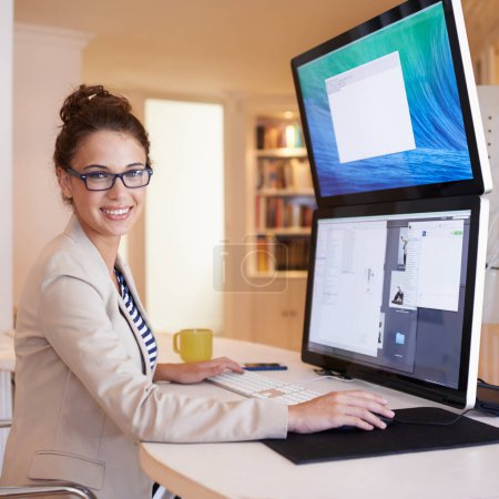 Foto de ¿Ha hecho la actualización a pantalla dual. Retrato de una joven que trabaja en una computadora de doble pantalla en casa - Imagen libre de derechos