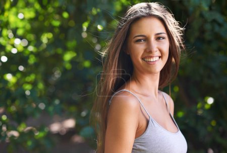 Photo for Shes always happiest outdoors. A beautiful young woman standing outdoors in summer - Royalty Free Image