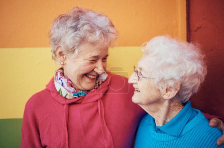 Freunde, Glück und Ruhestand mit einer Seniorin und einem Freund im Freien zusammen auf einem farbigen Wandhintergrund. Lächeln, Freiheit und Brille mit reifer Frauenfreundschaft oder Lachen draußen.