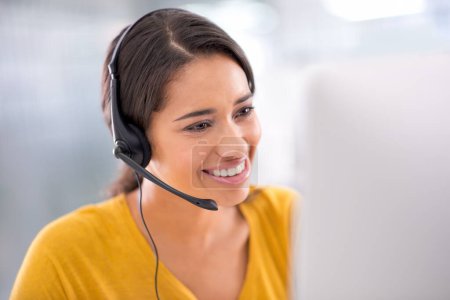 Wir beraten Sie telefonisch. eine junge Kundendienstmitarbeiterin trägt ein Headset, während sie am Computer sitzt