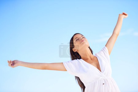 Téléchargez les photos : Complètement libre... Une jeune femme insouciante debout les bras tendus contre un ciel bleu - en image libre de droit