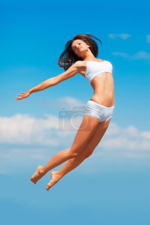 Foto de En lo alto del cielo. una joven feliz saltando alto en el cielo con su cuerpo extendido - Imagen libre de derechos