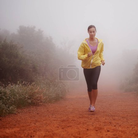 Photo pour Courir tôt le matin. une femme courant sur un sentier par un matin brumeux - image libre de droit