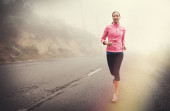 Keep putting one foot in front of the other. A young woman jogging on a country road on a misty morning Poster #625434038