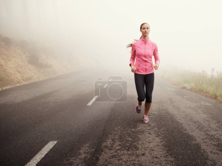 Misty morning runner. a young female jogger on a misty country road in the morning Poster 625452404