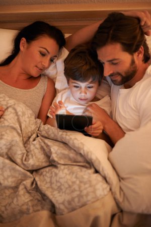 Foto de Storytime in the modern age. Un disparo de un niño pequeño usando una tableta mientras está acostado en la cama - Imagen libre de derechos