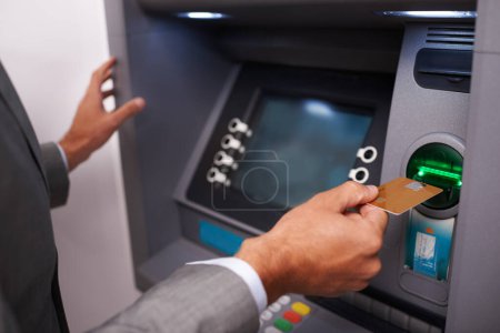 Téléchargez les photos : Faire un retrait rapide d'argent. un homme d'affaires insérant sa carte bancaire à un guichet automatique - en image libre de droit