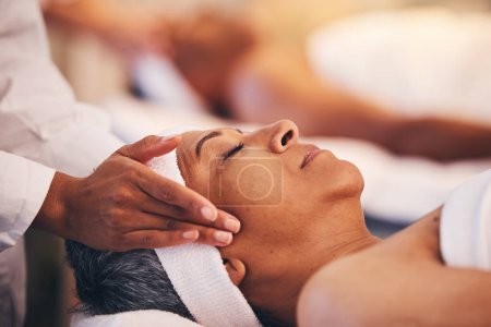 Hands, head and massage with a woman in a spa for wellness or luxury treatment to relax and rest. Face, zen and stress relied with a senior female relaxing in a health salon for physical therapy.