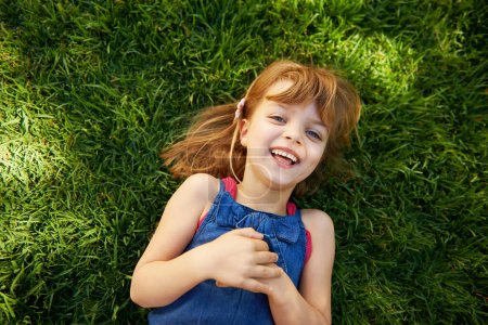 Photo for Sunny day fun. a cute little girl smiling while lying down on grass - Royalty Free Image