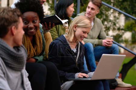 Photo for Working on her project. a group students looking at a laptop on campus - Royalty Free Image