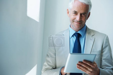 C'est l'heure des affaires. Portrait d'un homme d'affaires mature utilisant une tablette numérique
