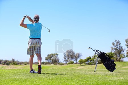 Téléchargez les photos : Une sacrée balade. Vue arrière d'un golfeur masculin mature jouant sur le terrain de golf - en image libre de droit