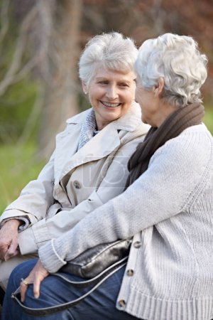 Foto de Ponerse al día con un viejo amigo. Dos mujeres mayores sonrientes sentadas juntas al aire libre - Imagen libre de derechos