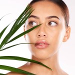 Leaf, beauty and woman with heatlhy skincare, natural cosmetics and wellness, glow and sustainability on studio background. Beautiful model face, green leaves from plants and eco friendly dermatology.
