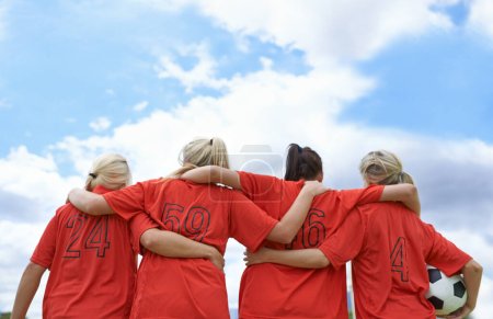 Foto de Psicología para el partido. Un equipo de fútbol femenino de pie con sus brazos alrededor de los hombros de los demás mirando hacia el campo - Imagen libre de derechos