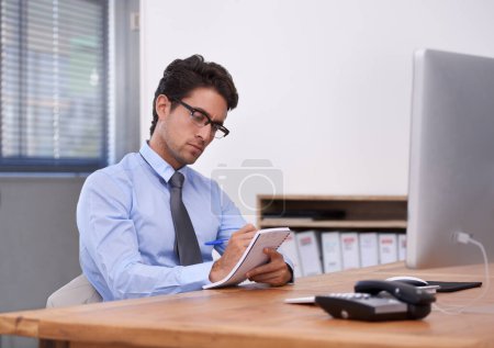 Photo for Writing down some great business ideas. Handsome young businessman writing down notes in his notebook - Royalty Free Image