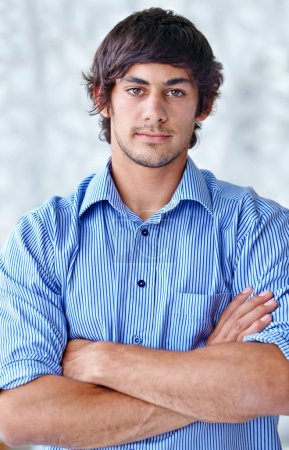Photo for Hes a responsible young executive. A handsome young man standing with his arms folded - Royalty Free Image