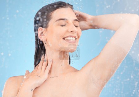 Photo for Woman, shower and cleaning for hygiene, bodycare and beauty with water on a blue studio background. Skincare, body care and female showering or washing and cleansing the skin in grooming routine. - Royalty Free Image