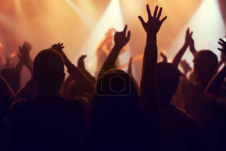 Photo for Music, lights and hands of crowd at concert for party, disco and live band performance. Dance, nightclub and silhouette of audience listening to artist on stage at festival for energy, rave and event. - Royalty Free Image