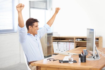 Photo for What a great year weve had. a young businessman raising his arms in victory while sitting at his desk - Royalty Free Image