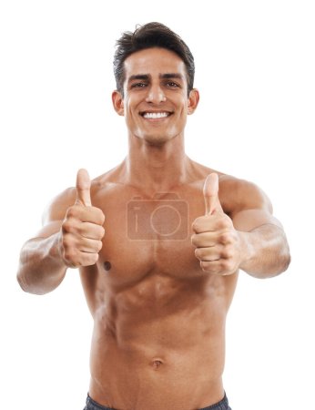 Feeling positive about his healthy lifestyle. Portrait of a handsome young shirtless man smiling and showing thumbs up against a white background