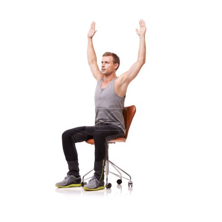 Foto de Estirándose en su asiento. Un joven guapo usando ropa de gimnasio y estirándose mientras está sentado en una silla de oficina sobre un fondo blanco - Imagen libre de derechos