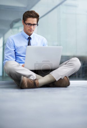 Photo for Waiting for his office furniture - Company startup. A young businessman sitting on the floor of his empty office working on a laptop - Royalty Free Image