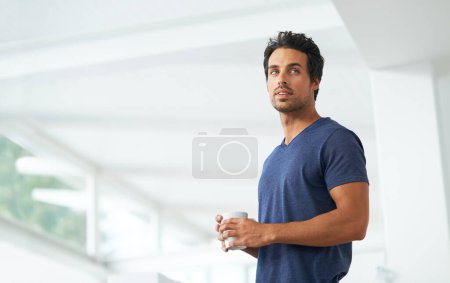 Photo for Getting his daily cup of caffeine. A handsome young man enjoying a cup of coffee at home - coppyspace - Royalty Free Image
