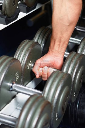 Photo for Time to pump that iron. Cropped image of a man picking up a dumbell - Royalty Free Image