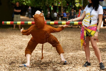 Foto de Un asunto de monos. Un joven con un traje de mono haciendo el limbo en un festival al aire libre - Imagen libre de derechos