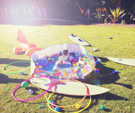 Foto de Man, backyard and passed out on grass, drinking and party in summer at with butt open in kids pool. Drunk person, sleeping and lawn with toys, sunshine or hangover on vacation, holiday or celebration. - Imagen libre de derechos