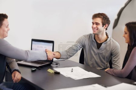 Photo for Sealing the deal. Young couple in a car salemans office signing paperwork for a new car - Royalty Free Image