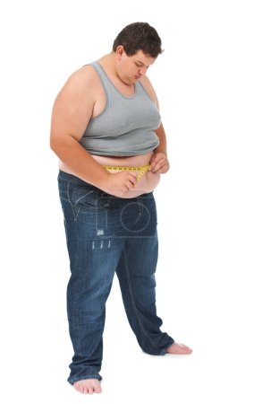 Auf sein Gewicht achten. Ein fettleibiger junger Mann misst seine Taille mit einem Maßband vor weißem Hintergrund