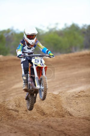 Photo for Hitting each ramp with purpose. A motocross rider taking a small jump - Royalty Free Image