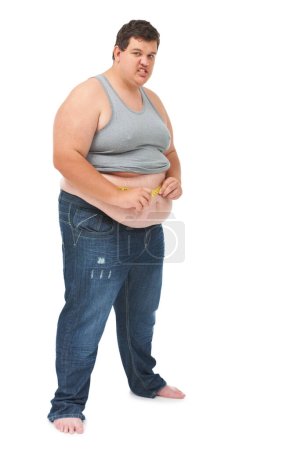 Téléchargez les photos : Pas le résultat qu'il voulait. Portrait d'un jeune homme obèse mesurant sa taille avec un ruban à mesurer sur un fond blanc - en image libre de droit